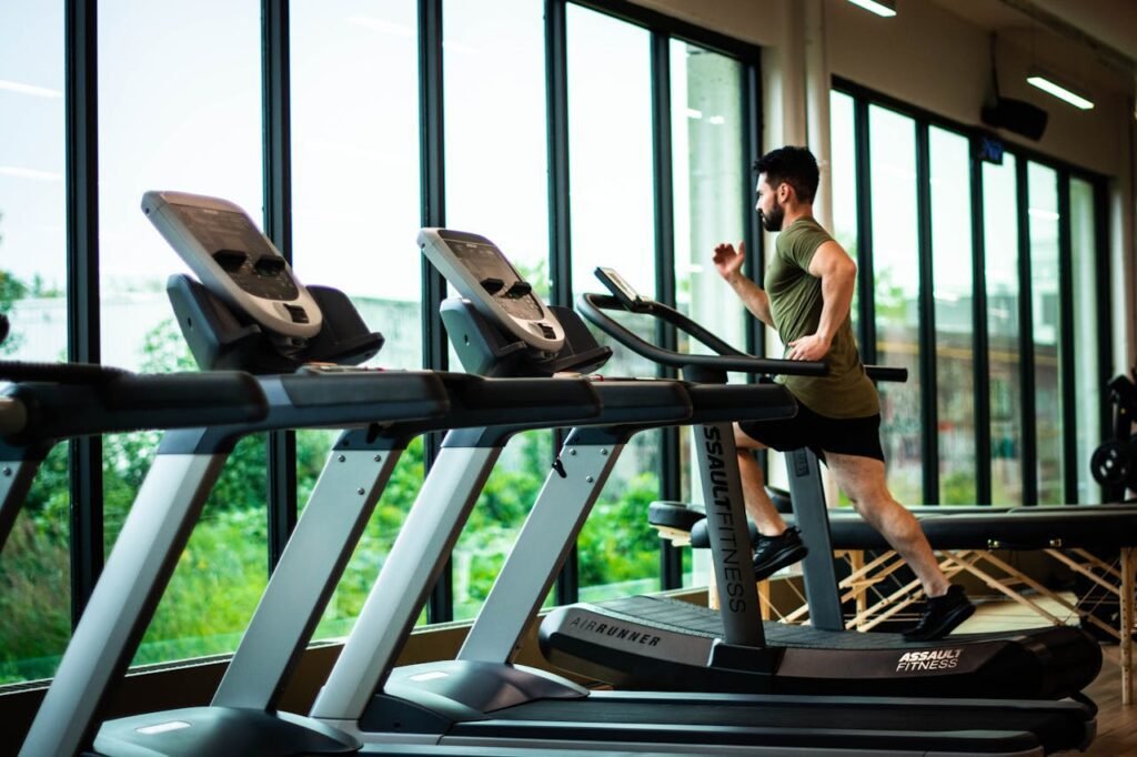 Man running on a treadmill in a gym, demonstrating a high-intensity interval training (HIIT) workout to boost energy and reduce fatigue