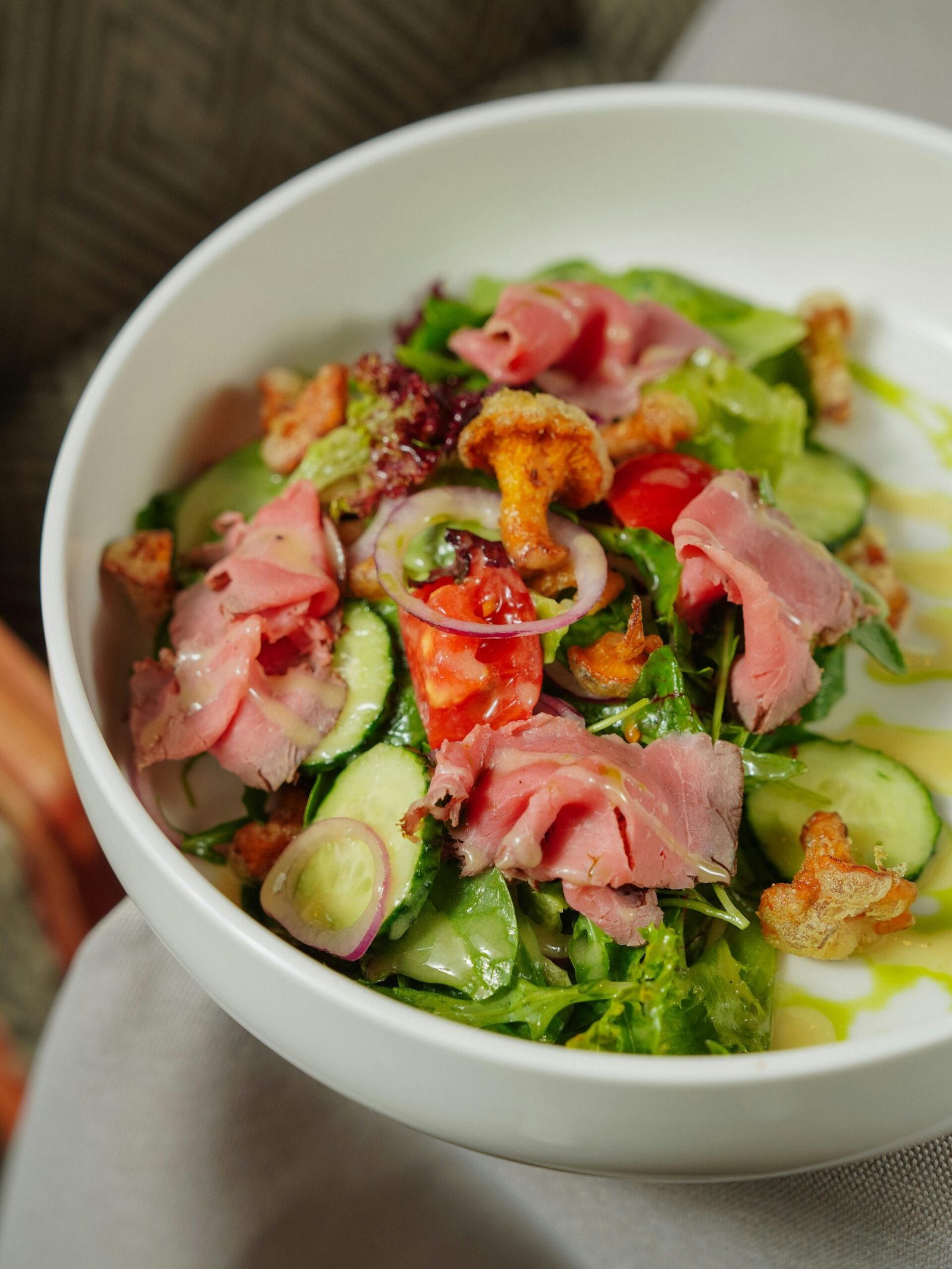 A bowl of nutrient-rich food featuring fresh spinach, sliced cucumbers, tomatoes, onions, cauliflower, and prosciutto, showcasing a colorful and balanced mix of vegetables and smoked meat to highlight the importance of micronutrient diversity.