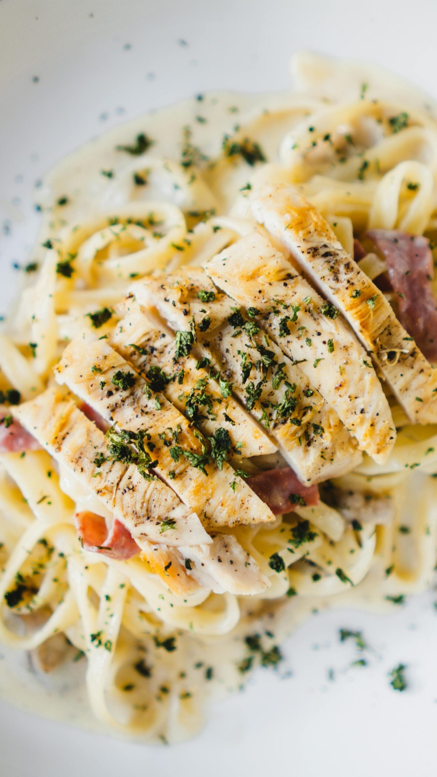 A delicious plate of chicken tenderloin fettuccine alfredo garnished with parsley.