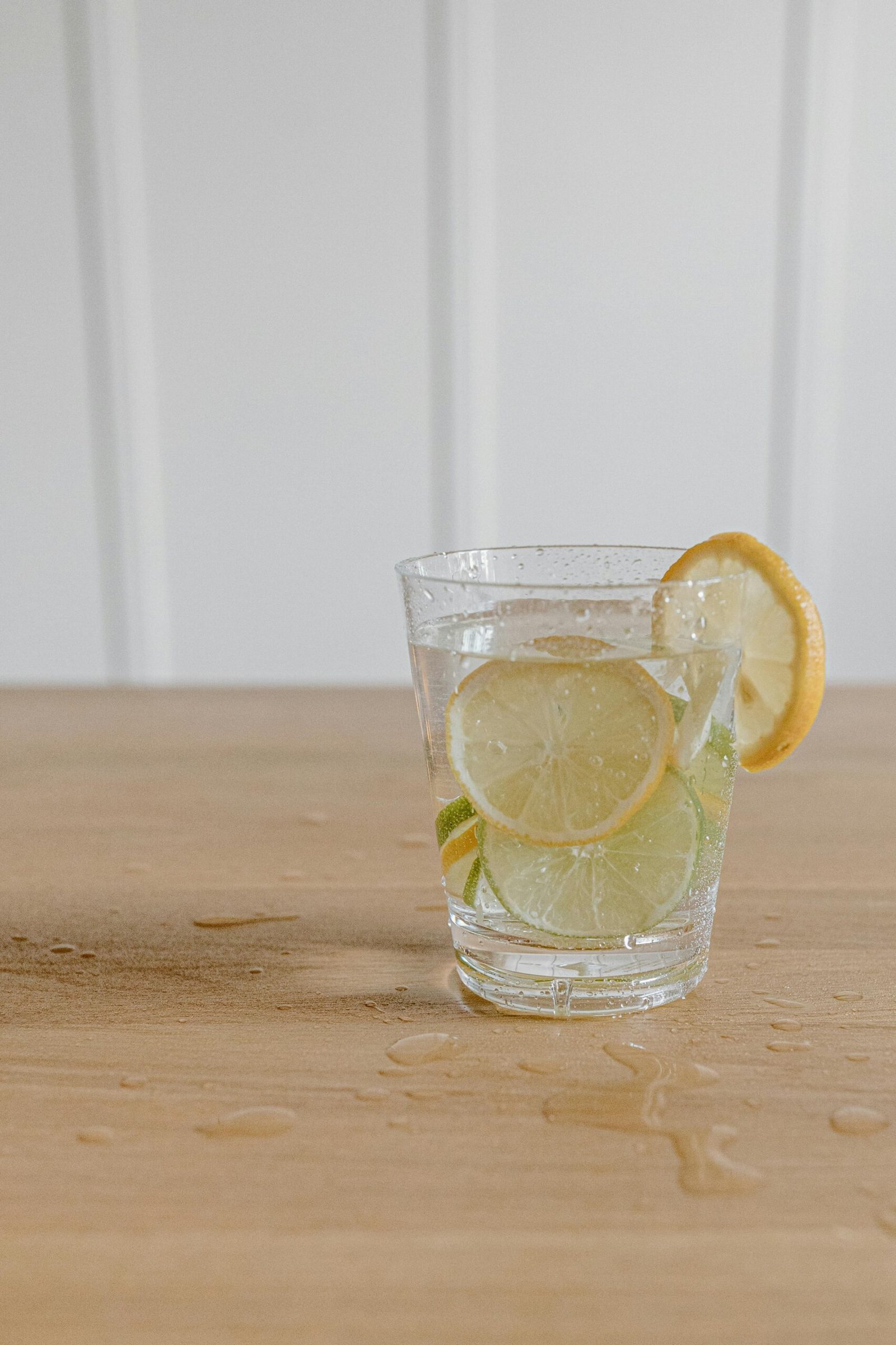 Glass of water with lemon slice on a wooden table.