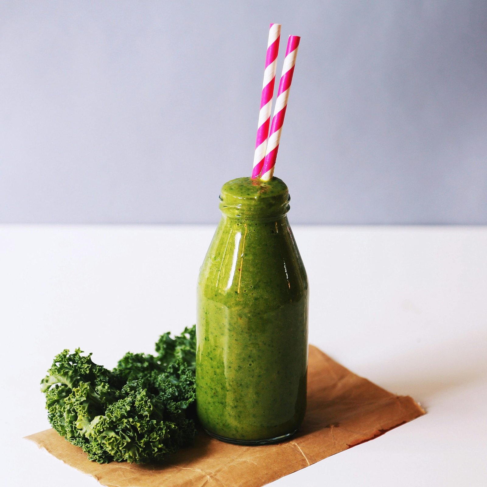 Fresh green smoothie and vegetables on a table, symbolizing a healthy post-holiday reset.