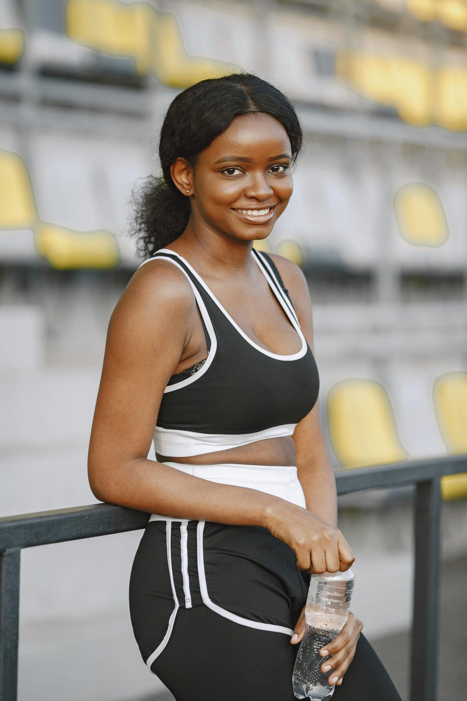 Person smiling with a water bottle outdoors after a workout.